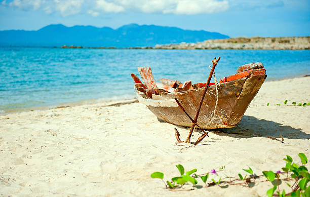 Old fisherman boat with anchor on the beach stock photo