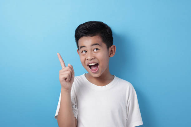 istock Happy Asian boy pointing finger up, having idea gesture 1246685747