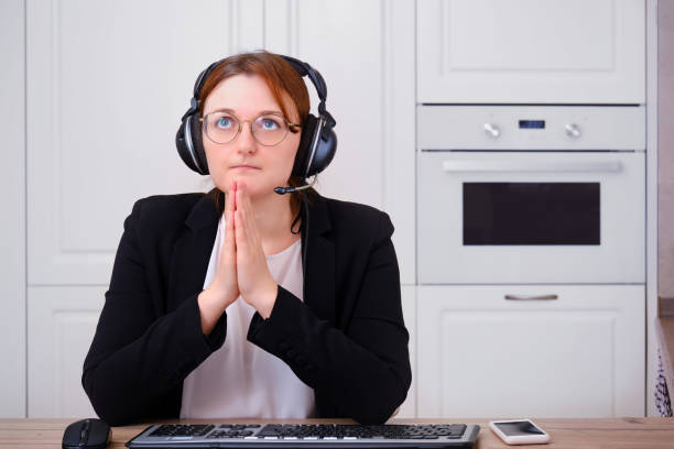 a woman prays to god at a computer during isolation due to a coronavirus. religion and confession in online video call to the priest of the church under quarantine - prayer call imagens e fotografias de stock