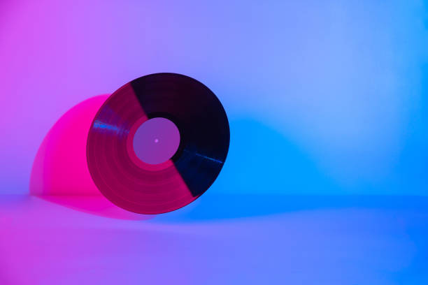 istock Black LP vinyl disc lit with colorful purple neon light on abstract background  with copy space 1246689358