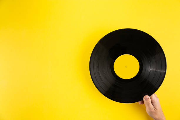 istock Hand holding vinyl record on abstract yellow background 1246689666