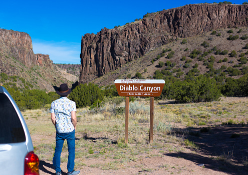 Santa Fe, NM: Tourist Looking at Diablo Canyon and Sign. The canyon is about 20 miles from Santa Fe in NM’s Rio Grande Valley.