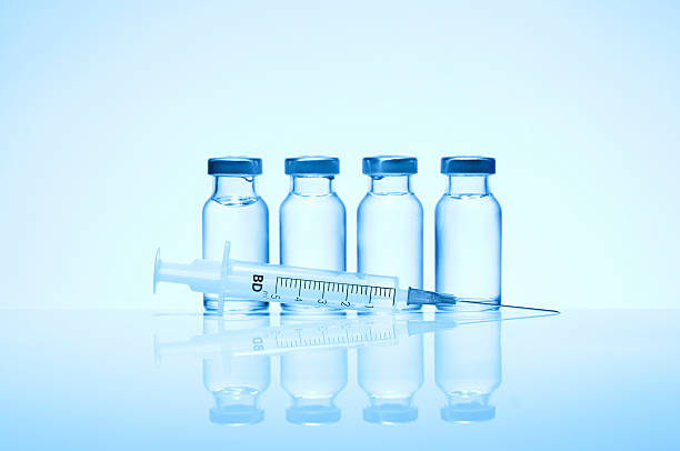 Monochromatic image of four glass vials and a syringe Medical Series--injection with blue effection. medicine vial stock pictures, royalty-free photos & images