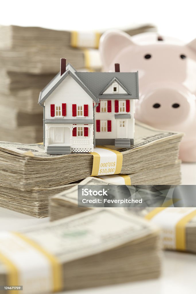 Small House and Piggy Bank with Stacks Money Small House and Piggy Bank with Stacks of Hundred Dollar Bills Isolated on a White Background. Business Stock Photo