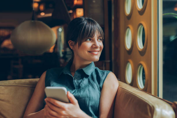 istock Beautiful Smiling Woman Using her Smartphone While Sitting at a Cosy Cafe 1246728437