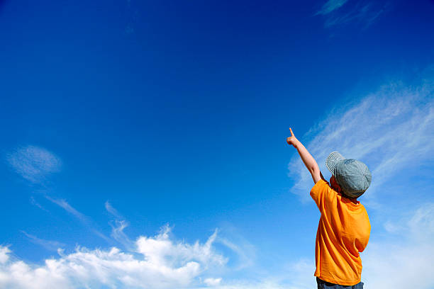 istock A boy with an orange shirt pointing at the sky 124674246