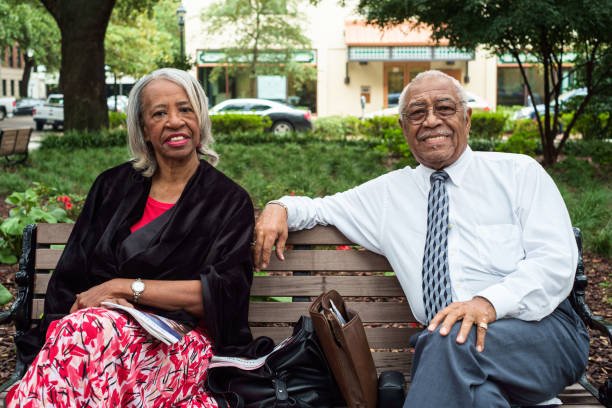 Retired Couple Savannah, Georgia - October 8, 2013: Seniord retired African American couple enjoying the afternoon at one of the popular city squares in the historic downtown district. senior adult women park bench 70s stock pictures, royalty-free photos & images