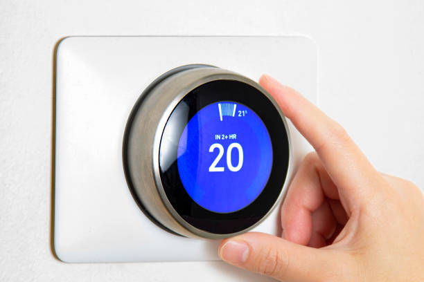 istock A person cooling down Home Air Conditioning, temperature is on centigrade celsius metrics using a smart thermostat on a white wall. 1246809902