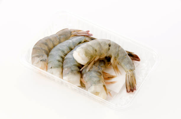 istock Fresh black tiger shrimp tails in plastic pack on white background 1246823346