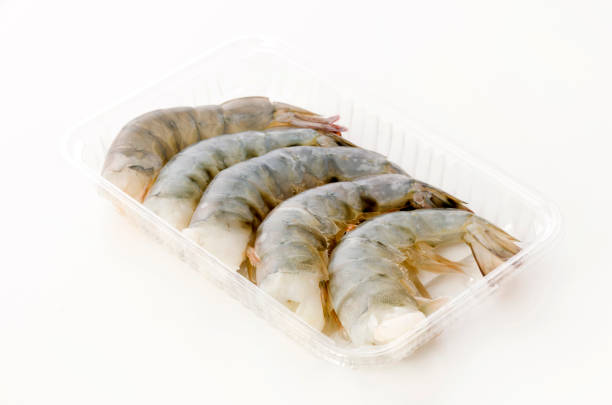 istock Fresh black tiger shrimp tails in plastic pack on white background 1246823852