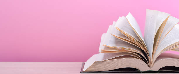 istock The book is open, lying on the table, sheets fanned out on a pink background. 1246832591