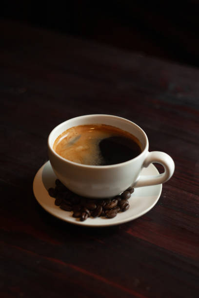Coffee cup and coffee beans on wooden table.