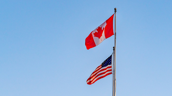 USA And Canada Flags Isolated On Blue Sky.