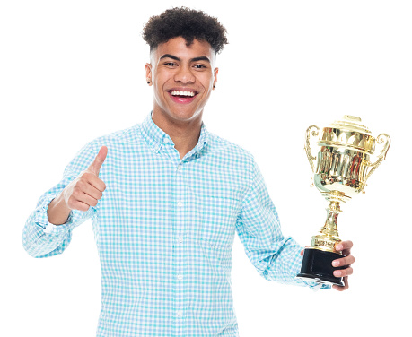 Front view of aged 18-19 years old with curly hair generation z teenage boys standing in front of white background wearing button down shirt who is successful and winning and showing award who is in first place and holding trophy