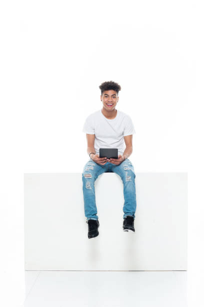 istock Generation z boys sitting in front of white background wearing jeans and using digital tablet 1246902977