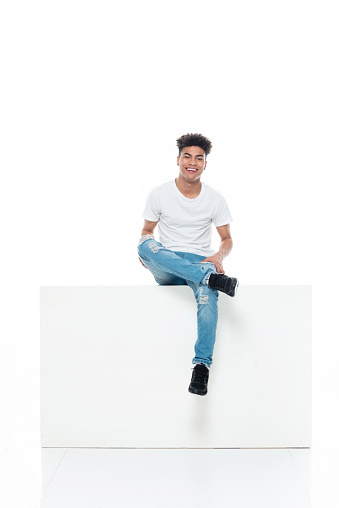 Front view of aged 18-19 years old with curly hair african ethnicity boys resting in front of white background wearing shirt who is laughing