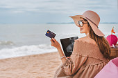 Asian woman holding credit card for online shopping at the beach.