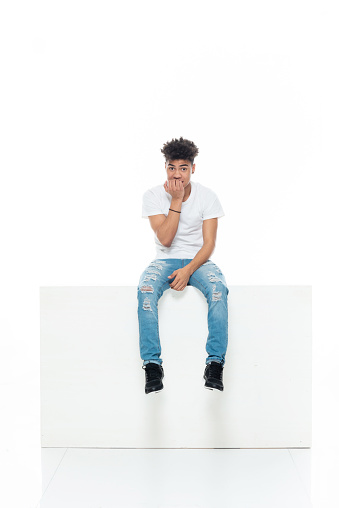 Full length of aged 18-19 years old with curly hair african ethnicity boys resting in front of white background wearing shirt who is distraught