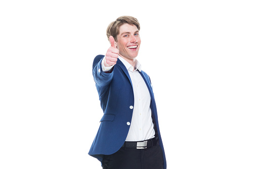Waist up of aged 20-29 years old caucasian young male in front of white background wearing blazer who is smiling and showing thumbs up