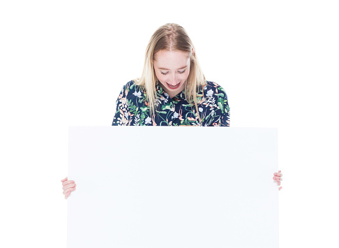 Waist up of aged 20-29 years old who is beautiful caucasian young women in front of white background wearing pajamas who is smiling who is showing with hand and holding placard with copy space