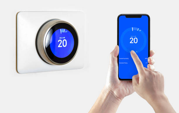 A person using a smart phone application cooling down the room temperature with a wireless smart thermostat on a white background. A person using a smart phone application cooling down the room temperature with a wireless smart thermostat on a white background. smart thermostat photos stock pictures, royalty-free photos & images