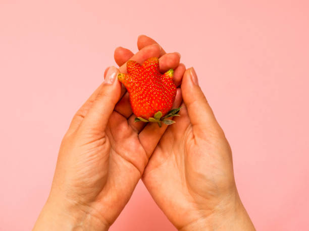 istock Ugly food: unusual strawberry in a woman hands 1246921762