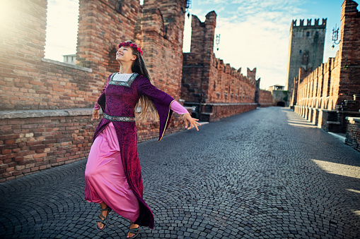 Happy Juliet Capulet running on street on Verona bridge. \nNikon D850.