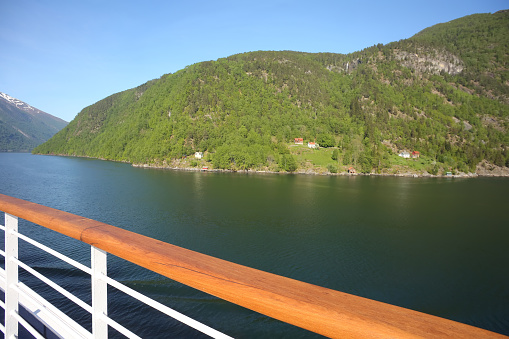Deck of a ship as it cruises down the Sognefjord or Sognefjorden,  Vestland county in Western Norway. Beautiful landscape with reflections in the fjord of the mountains.