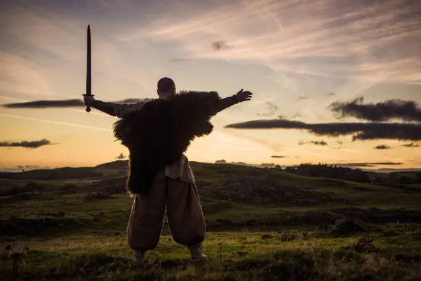 A lone redhead individual Scottish viking sword wielding warrior man on a moor