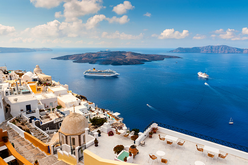 Santorini, Greece - 20th September 2012: Wide angle view of the cliff side buildings and large cruise ships in Santorini, Greece. Santorini is a small Greek island and popular holiday destination.