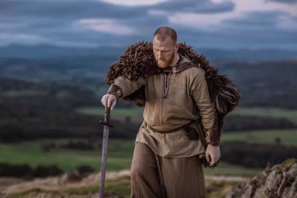 A lone redhead individual Scottish viking sword wielding warrior man on a moor