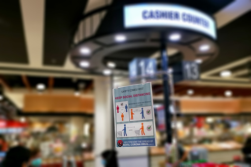 A poster encouraging shoppers to maintain social distancing at cashier counter in Malaysia.