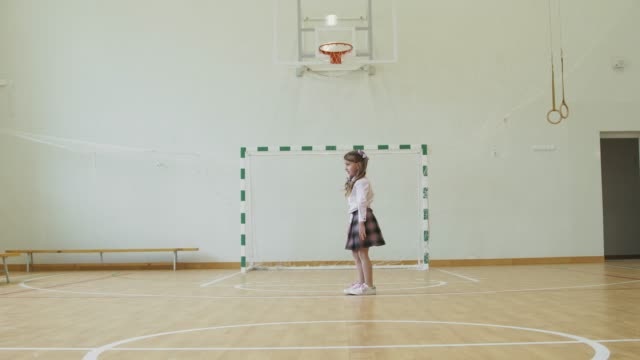 Little girl sits on the twine in the school gym. Girl performs gymnastic twine in the gym.