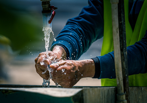 Workers washing their hands at a makeshift fountain on a construction site