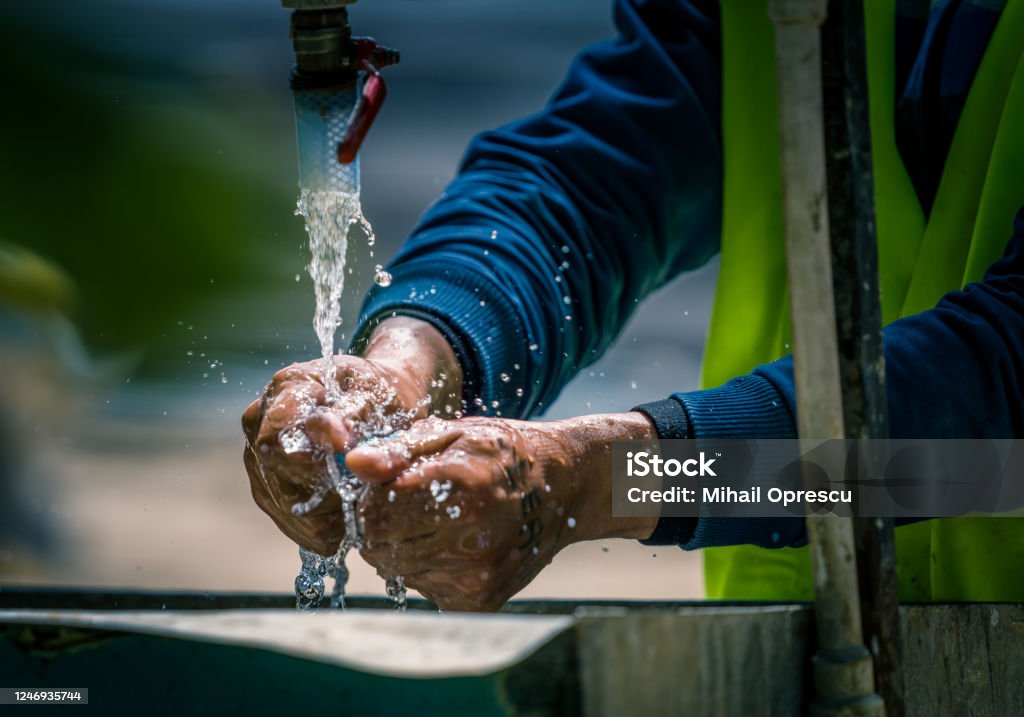 Life on a construction site Workers washing their hands at a makeshift fountain on a construction site Construction Site Stock Photo