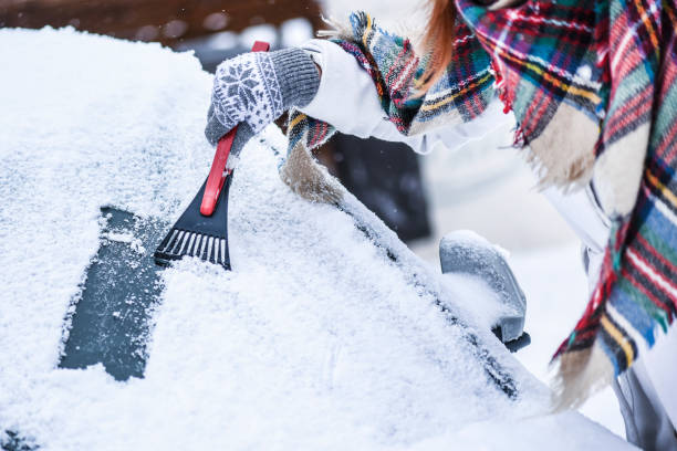kobieta czyszcząca śnieg z przedniej szyby, skrobanie zamarzniętego szkła lodowego. - snow car window ice scraper zdjęcia i obrazy z banku zdjęć