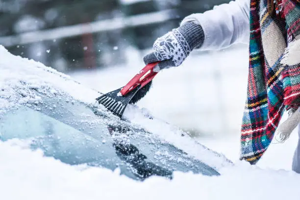 Photo of Woman cleaning snow from windshield, Scraping frozen ice glass.