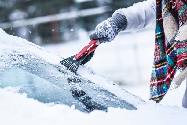 kvinna rengöring snö från vindrutan, skrapa fryst isglas. - winter storm bildbanksfoton och bilder