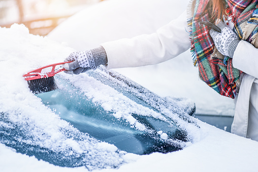 Woman cleaning snow from windshield, Scraping frozen ice glass. Winter car clean front windows.