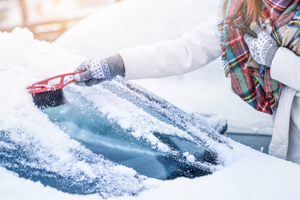 kobieta czyszcząca śnieg z przedniej szyby, skrobanie zamarzniętego szkła lodowego. - snow car window ice scraper zdjęcia i obrazy z banku zdjęć