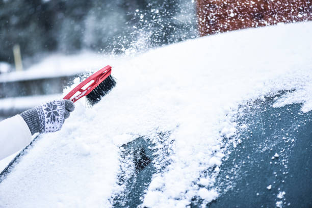 フロントガラスから雪を掃除する女性、凍った氷のガラスを削る。 - snow car window ice scraper ストックフォトと画像