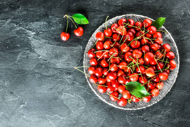 istock Cherries in wicker basket top view on dark or black stone table. 1246948278