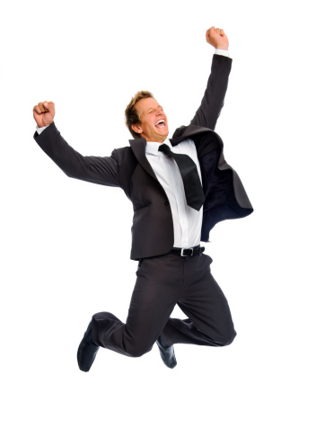 Attractive blond man celebrates his success by jumping raises his fist overhead 