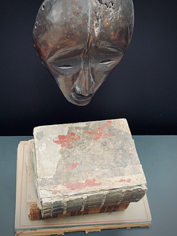 The reader: tribal african mask above vintage books