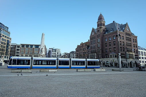 Tram driving on the empty Dam Square during the Corona crisis in the Netherlands