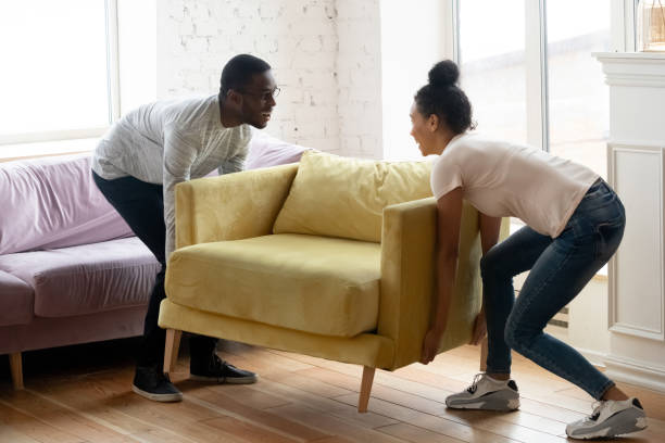 couples africains plaçant le nouveau fauteuil moderne dans le salon léger - activité physique photos et images de collection