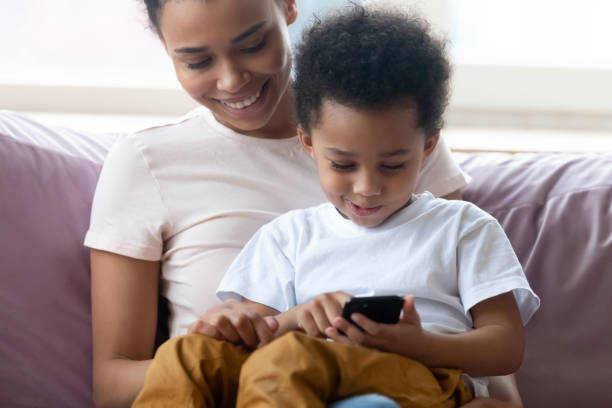 istock Son sit on mothers lap using smartphone play games 1246980275