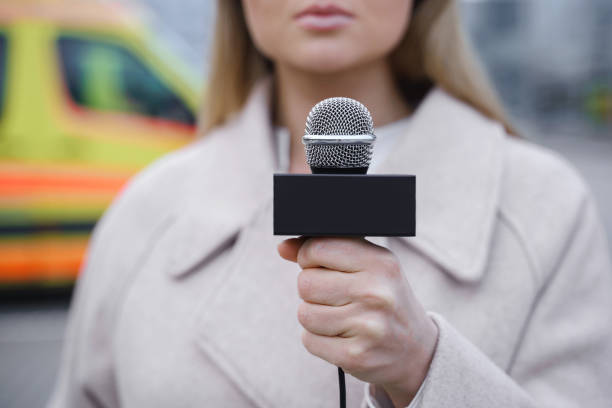 istock Journalist speaking into the microphone beside the ambulance vehicle 1246987996