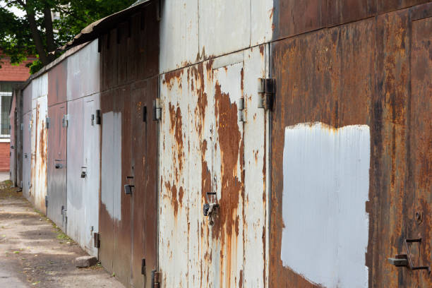 A row of old car garages on the street with closed rusty gates and doors.
