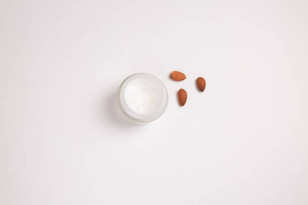 istock Round jar of cream near almonds. On a light background. 1247004297